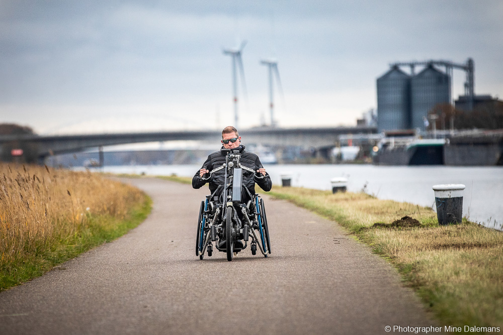 Sven beim handbiken entlang eines Flusses.